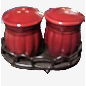 Cranberry colored salt and pepper shakers in metal holding rack